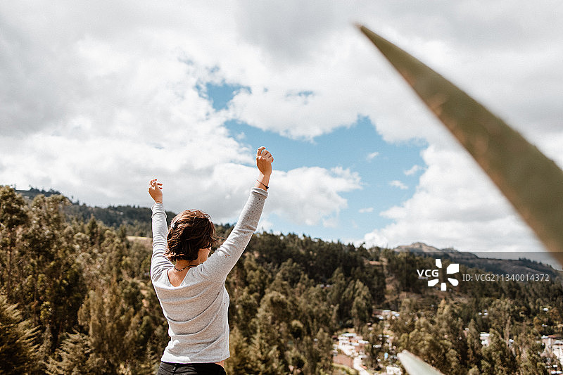 站在秘鲁卡哈马卡山上的举臂女子背影图片素材