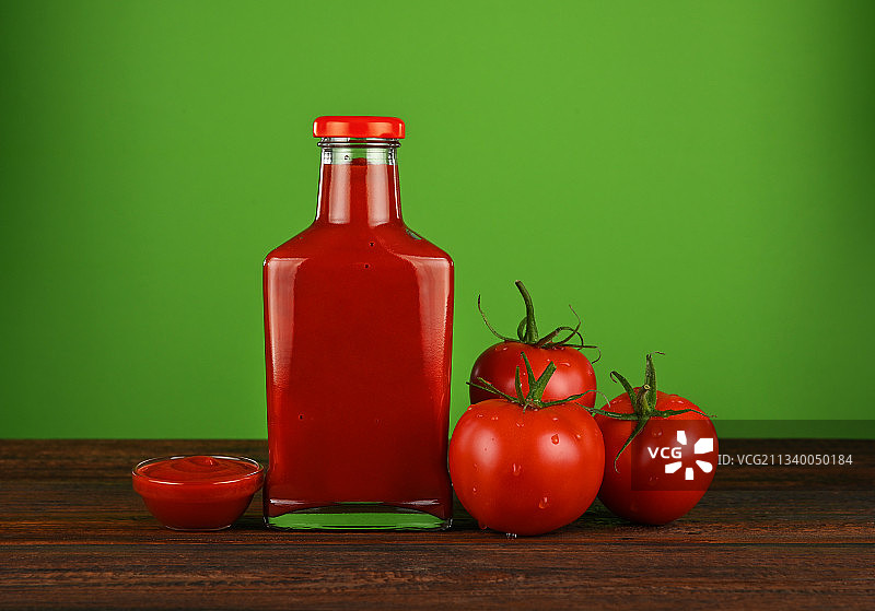 绿色背景下桌上的番茄和瓶子特写图片素材