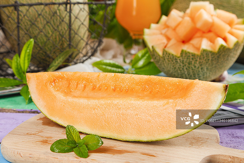 木板上放着切开的西州蜜25号哈密瓜图片素材