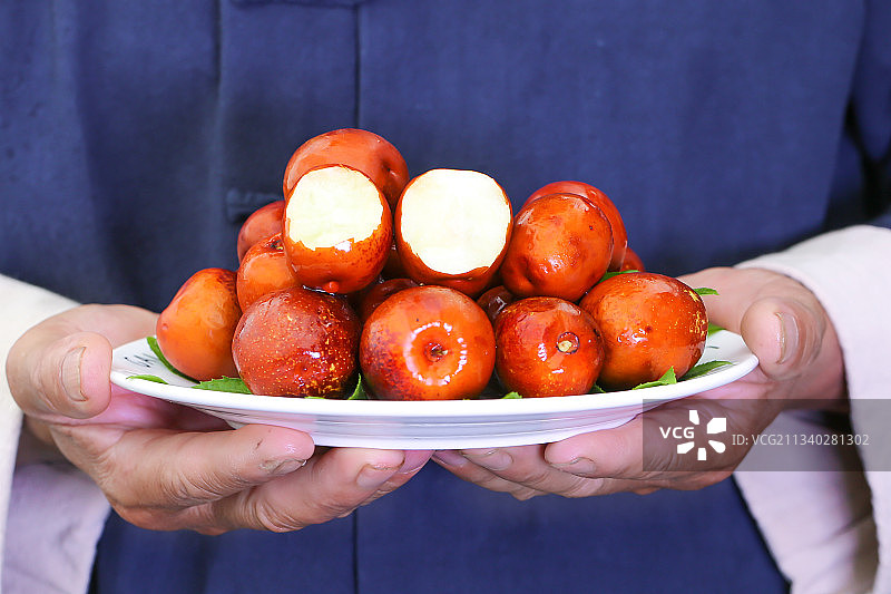 手里端着一盘冬枣图片素材
