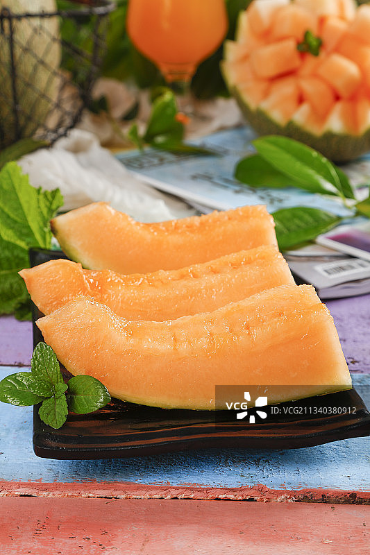 木板上放着切开的西州蜜25号哈密瓜图片素材