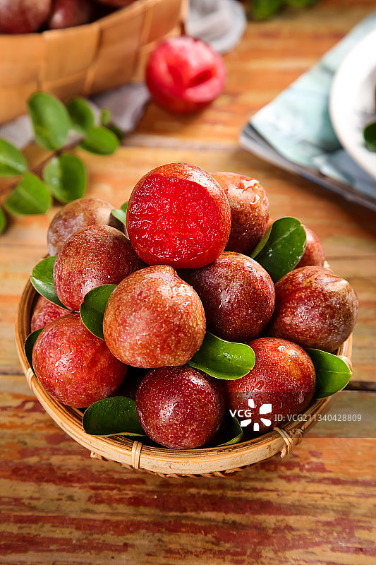 木板上放着一篮子红心李子图片素材