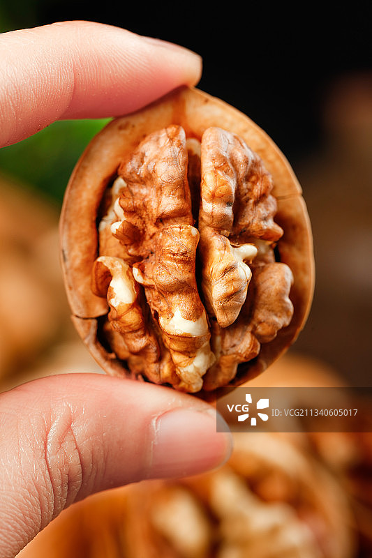 手拿剥开的碳烤核桃图片素材