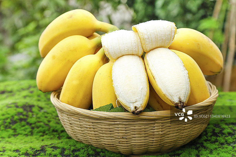 草地上放着一筐剥皮的苹果香蕉图片素材