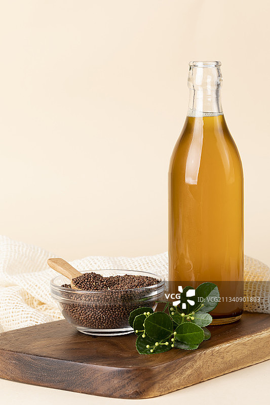 紫苏油玻璃瓶、紫苏籽碗和木勺在木板上图片素材