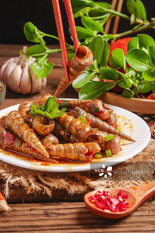 木底上放着一盘香辣钉螺图片素材