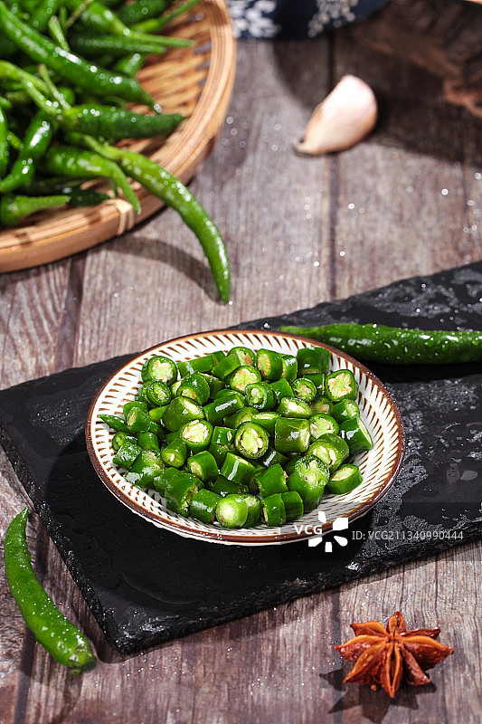 黑石板上放着一碟切开的青小米辣图片素材