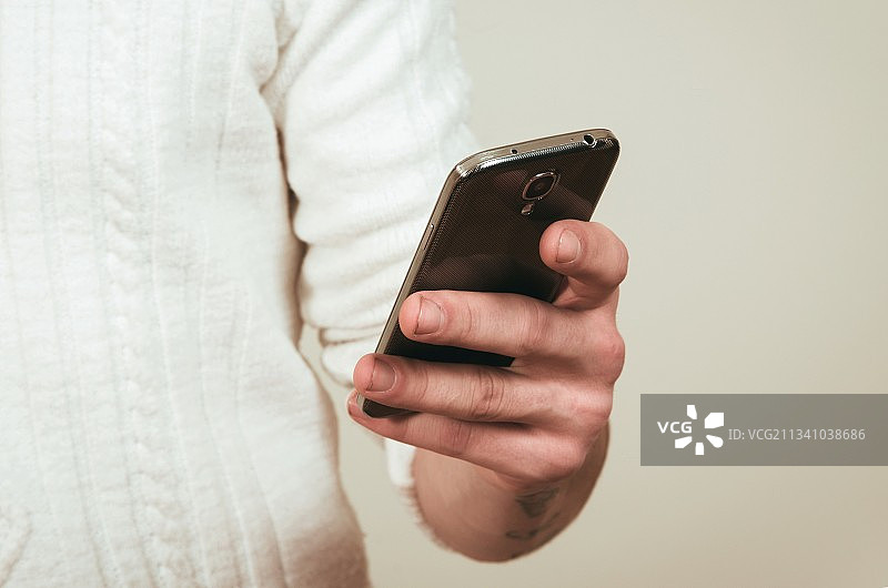 靠墙使用手机的男士的身体中部图片素材