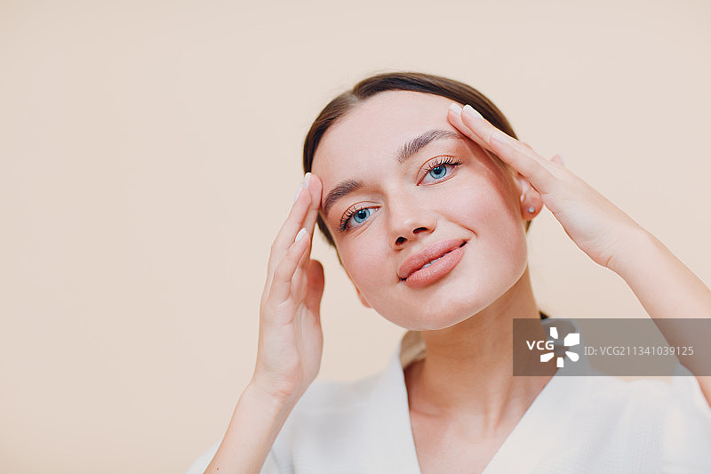 米色背景前的年轻女子肖像图片素材