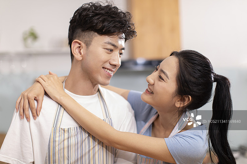 快乐的年轻夫妇在厨房做饭图片素材