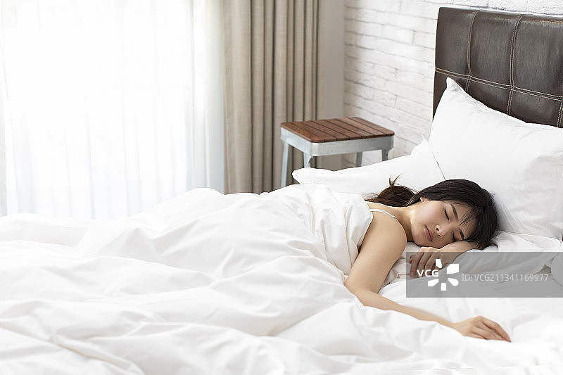 年轻女子躺在床上睡觉图片素材