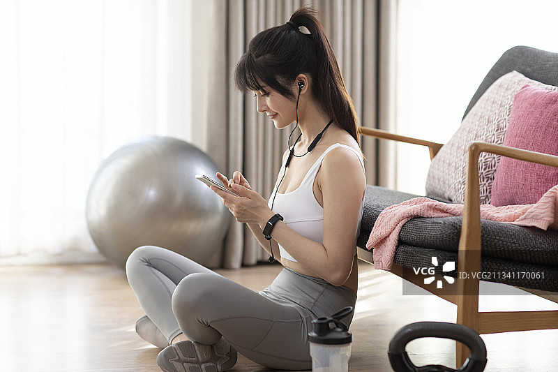 年轻女子运动后玩手机图片素材