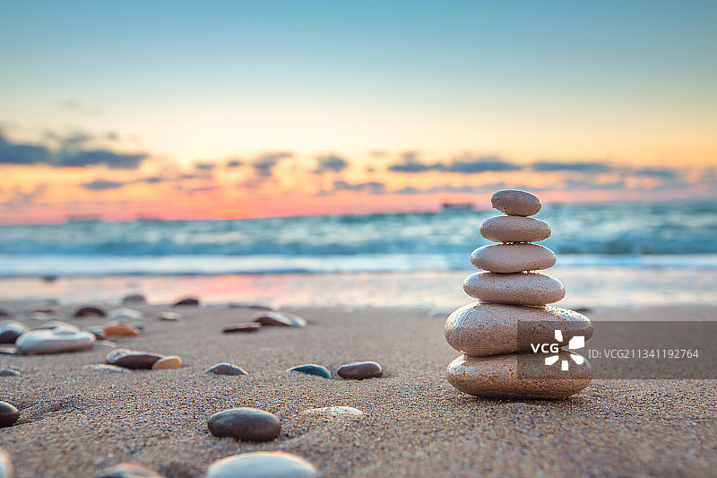 日落时海滩上堆叠的鹅卵石特写图片素材