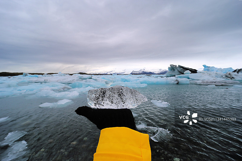 手持冰块，背景是冰岛冰川图片素材