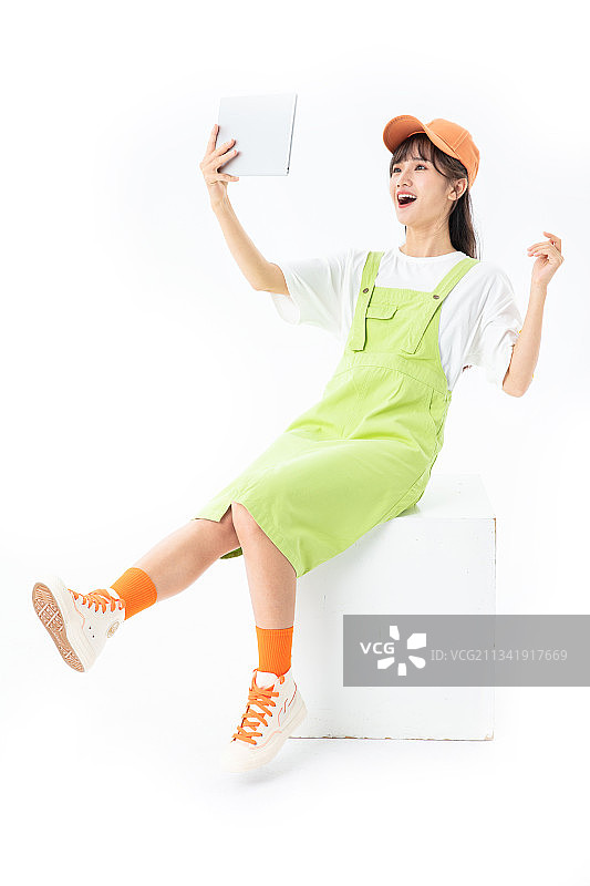 坐在木箱子上的年轻女生玩平板电脑图片素材