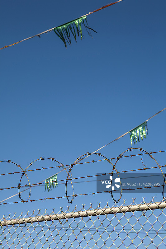 金属围栏、带刺铁丝网和闪光绿色彩带图片素材