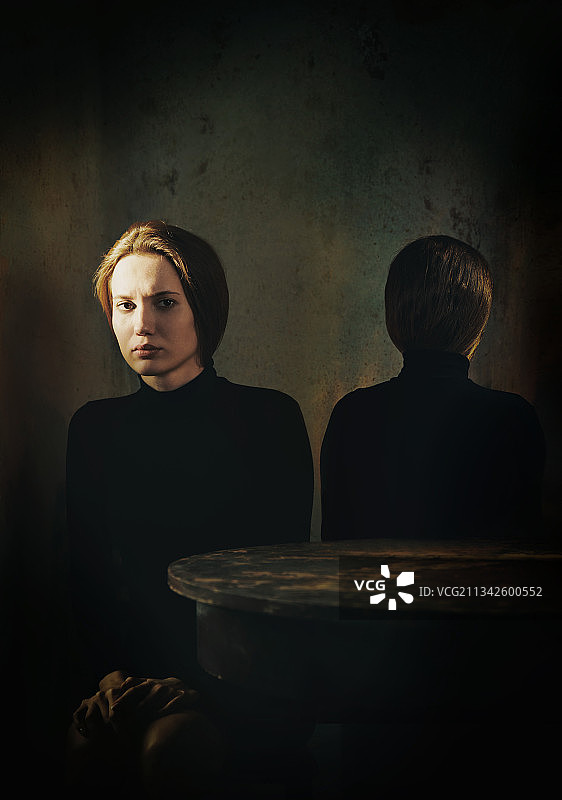 两名忧心忡忡的妇女坐在桌旁，面朝相反的方向。适合做书的封面图片素材