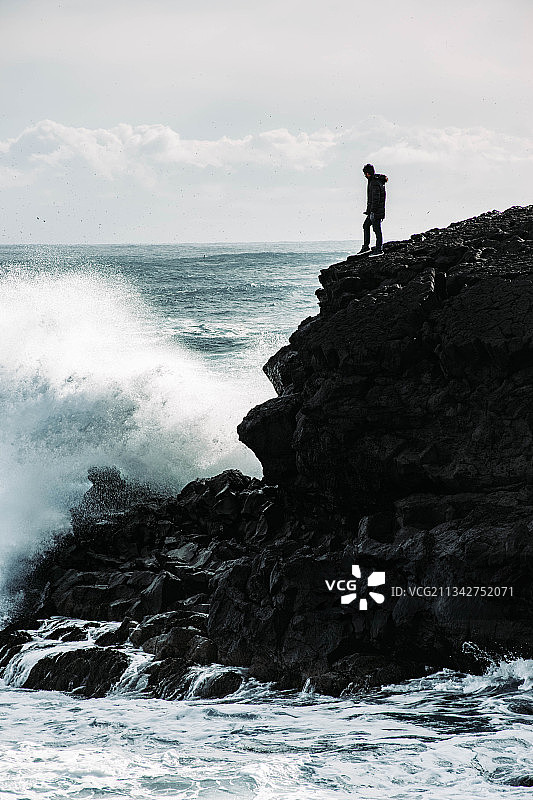 站在冰岛天空下海边岩石上的男人轮廓图片素材