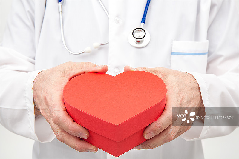 医生在白色背景前拿着心形图片素材