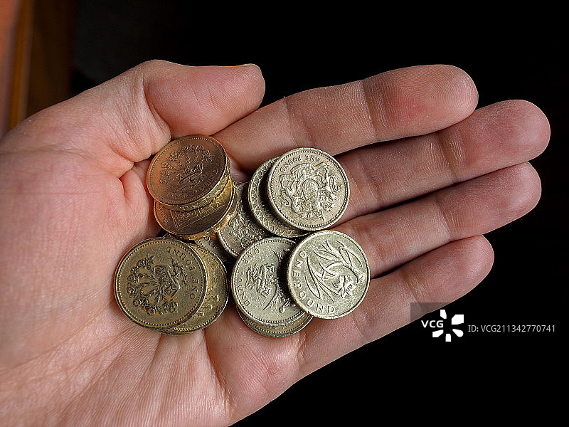 黑色背景上手持硬币的局部照片图片素材