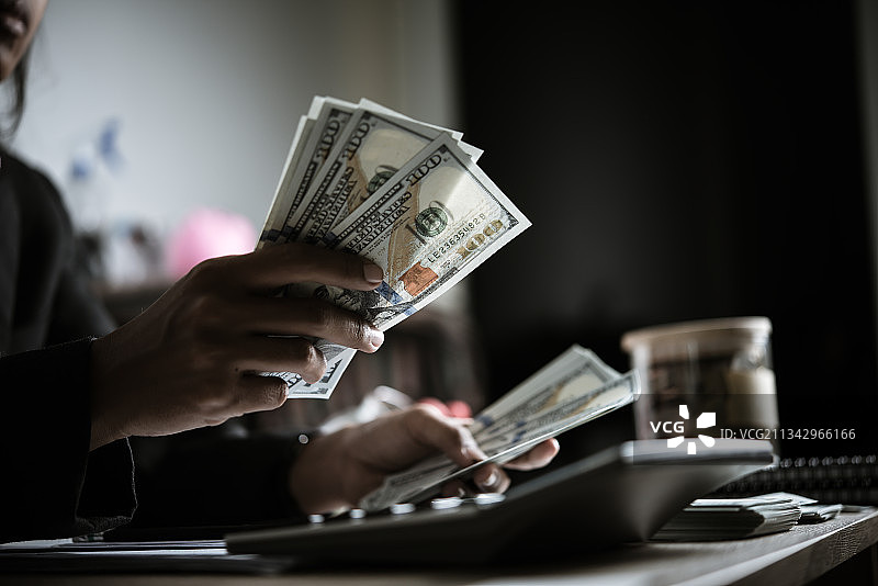 在桌子旁拿着纸币的商人的身体中部图片素材