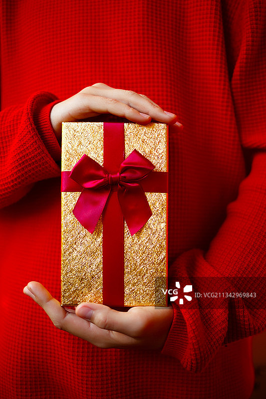 红色背景下，儿童手中的精美礼品图片素材