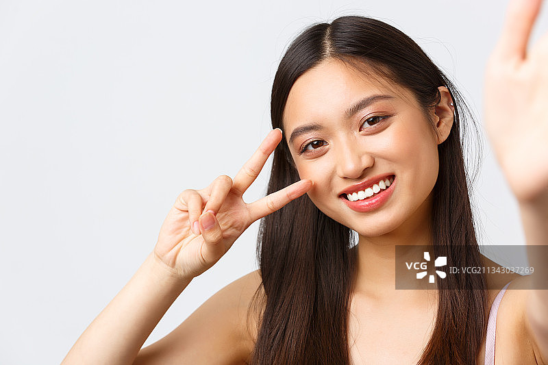 站在白色背景前做手势的微笑女人肖像图片素材