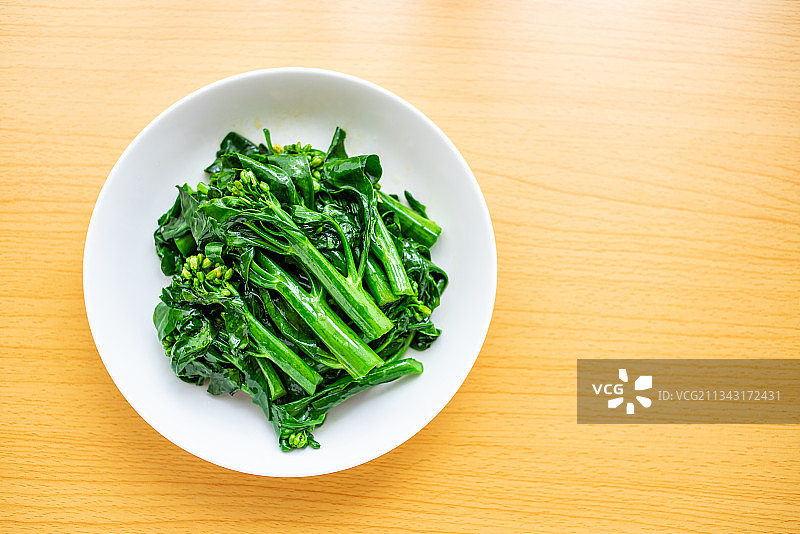 木桌面上一碟的绿色素菜炒芥蓝菜心图片素材