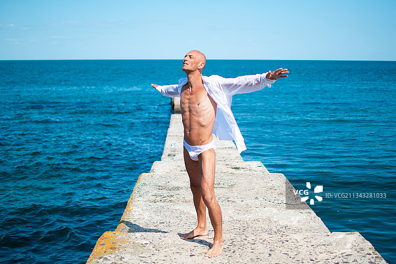 站在海上码头上欣赏天空的赤膊男人全身照图片素材