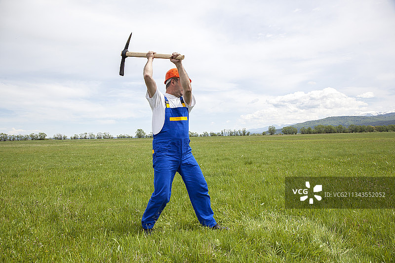 工人在绿色草地上用镐图片素材