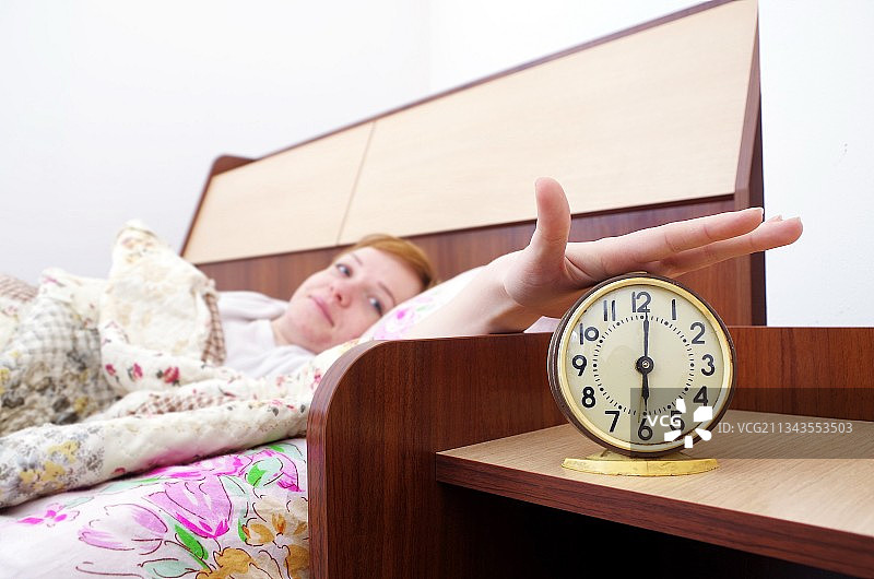 卧室里的女人与闹钟图片素材