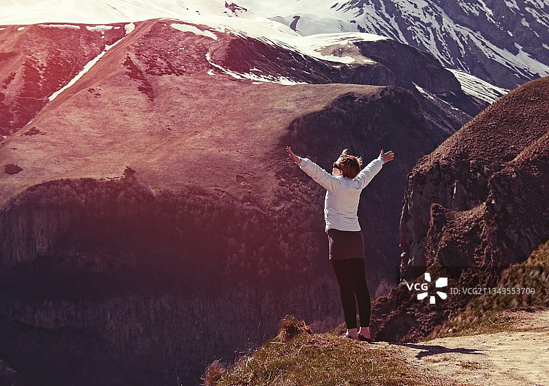 站在岩石上，以格鲁吉亚山脉为背景的女子背影图片素材