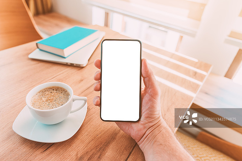 裁剪的手在桌子上拿着手机，塞尔维亚图片素材