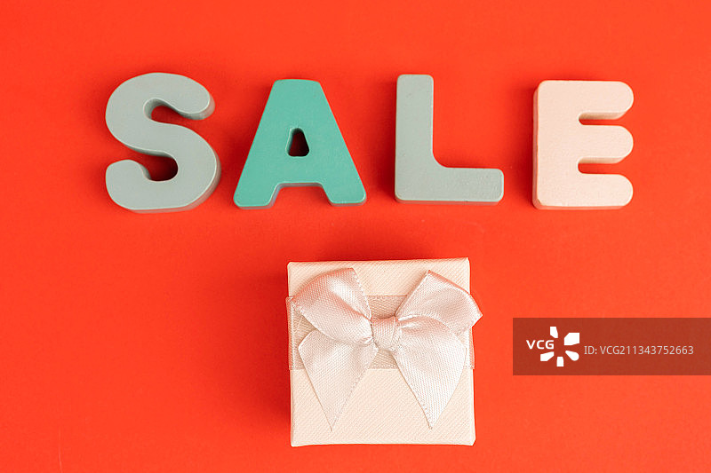 红色背景礼物盒旁边的SALE打折礼物图片素材