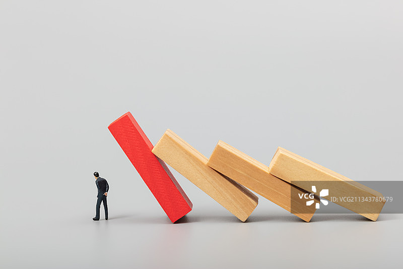 微缩创意倾倒的多米诺骨牌下的焦虑投资者图片素材