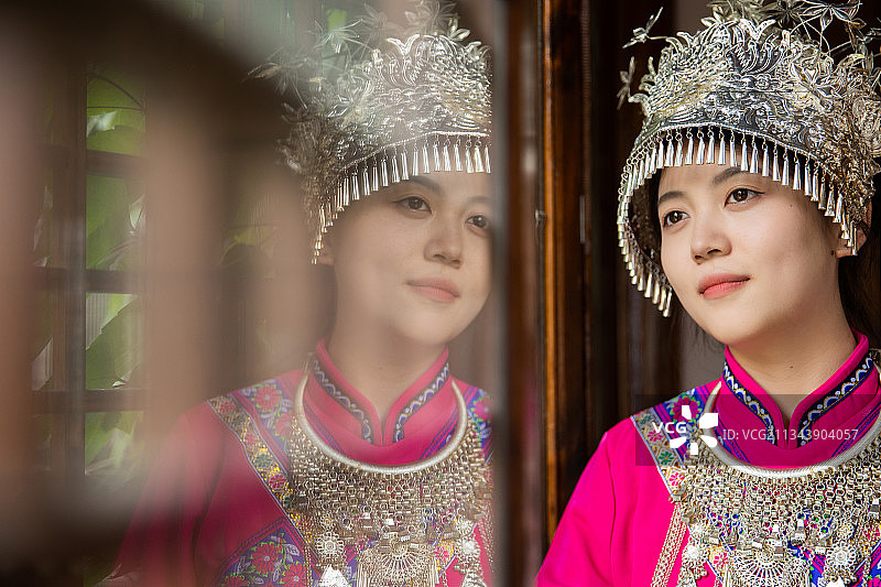 穿着土家族服饰的女孩望向窗外图片素材