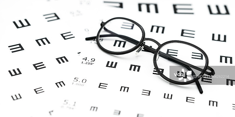 黑色眼镜放在视力表图纸上图片素材
