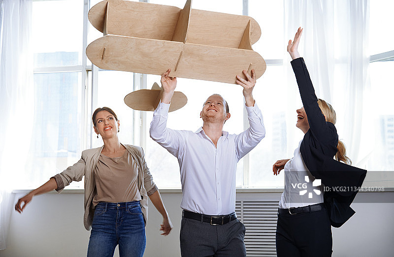 一群年轻商务人士在办公室玩大型飞机模型图片素材