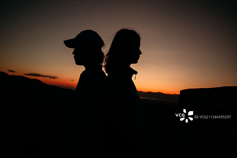 闺蜜在夕阳下背靠背剪影图片素材