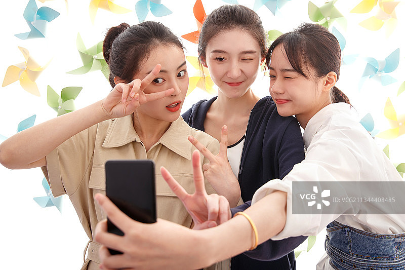 漂亮的年轻女孩们使用手机自拍图片素材