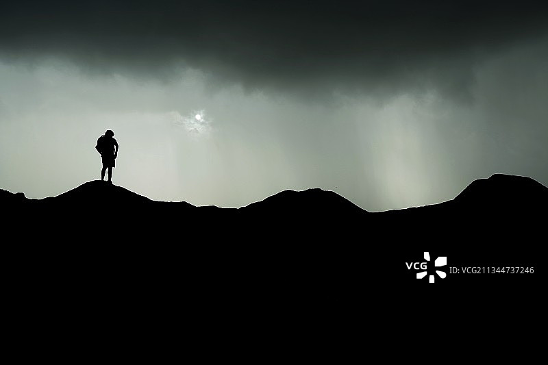 暴风云下站在山上的男人轮廓图片素材