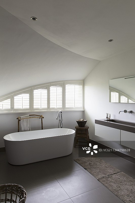 设计师浴室，拱形天花板和弧形窗户旁的独立式浴缸图片素材