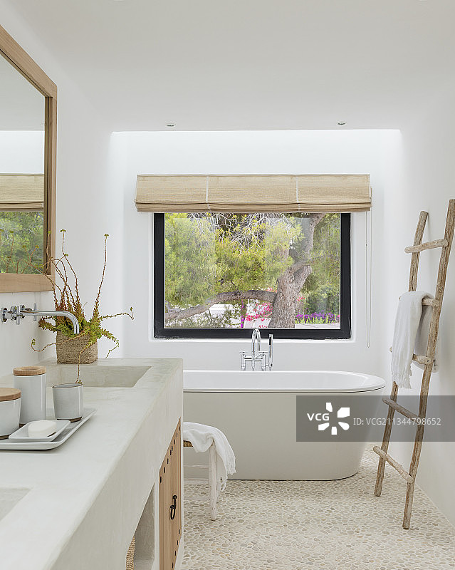 自然浴室中窗户下的独立式浴缸图片素材