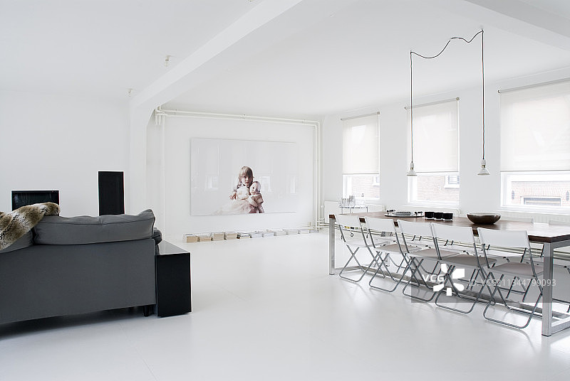 全白色开放式室内灰色沙发和长餐桌图片素材