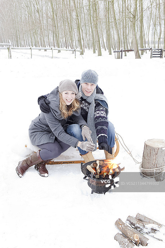在雪景中用火盆取暖的情侣图片素材