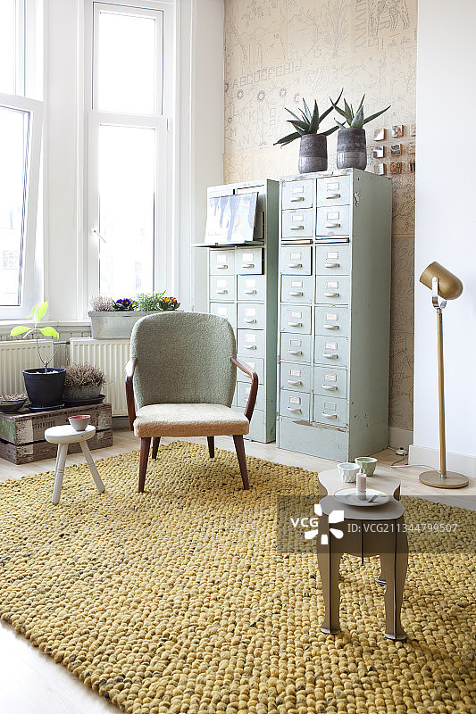 复古风格客厅中，两个高高的抽屉柜前方的复古扶手椅图片素材