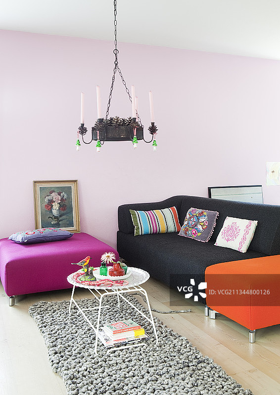 客厅里带有鲜艳色彩的脚凳和沙发，背景是淡粉色的墙壁图片素材