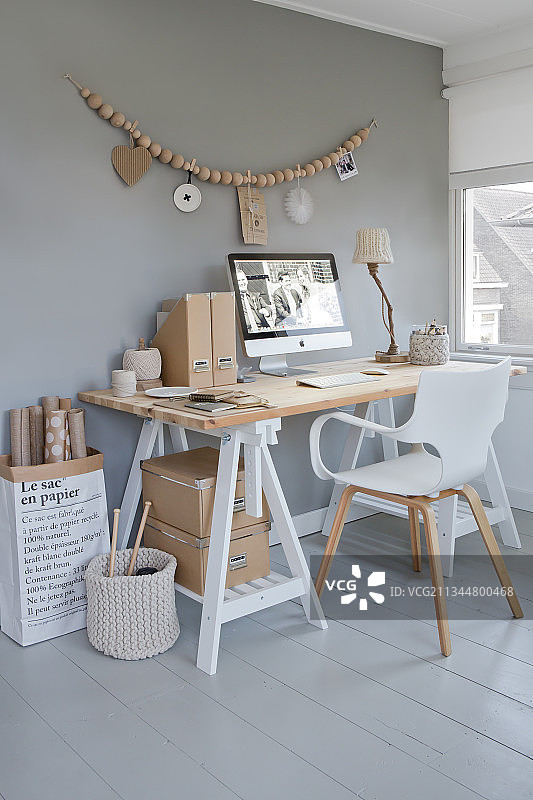 书房灰色墙壁上木珠挂饰下的书桌和白色椅子图片素材