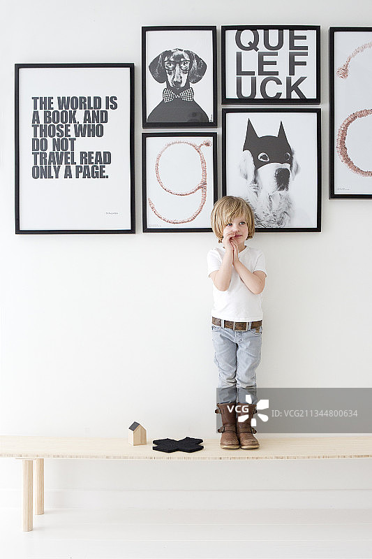 站在黑白标语海报下木凳上的小男孩图片素材