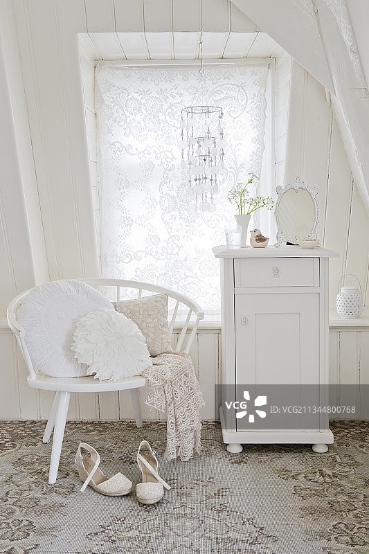 阁楼房间窗前的白色橱柜和带枕头的椅子图片素材